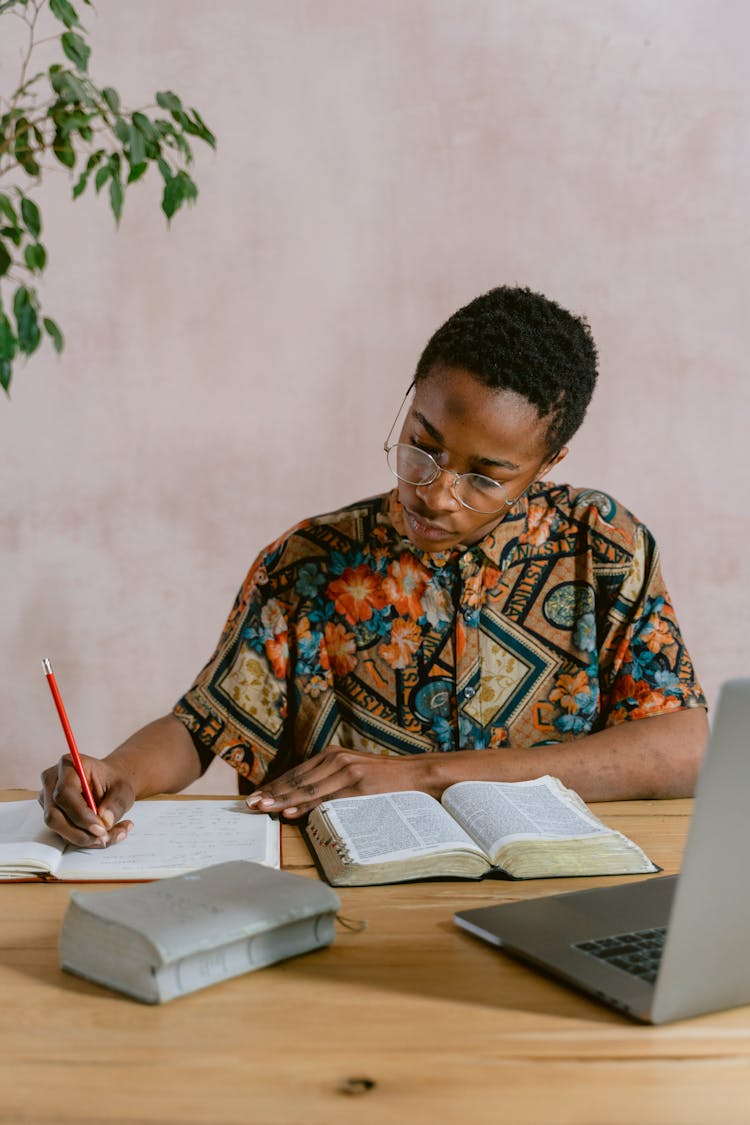 Man In Aztec Print Polo Writing On Notebook