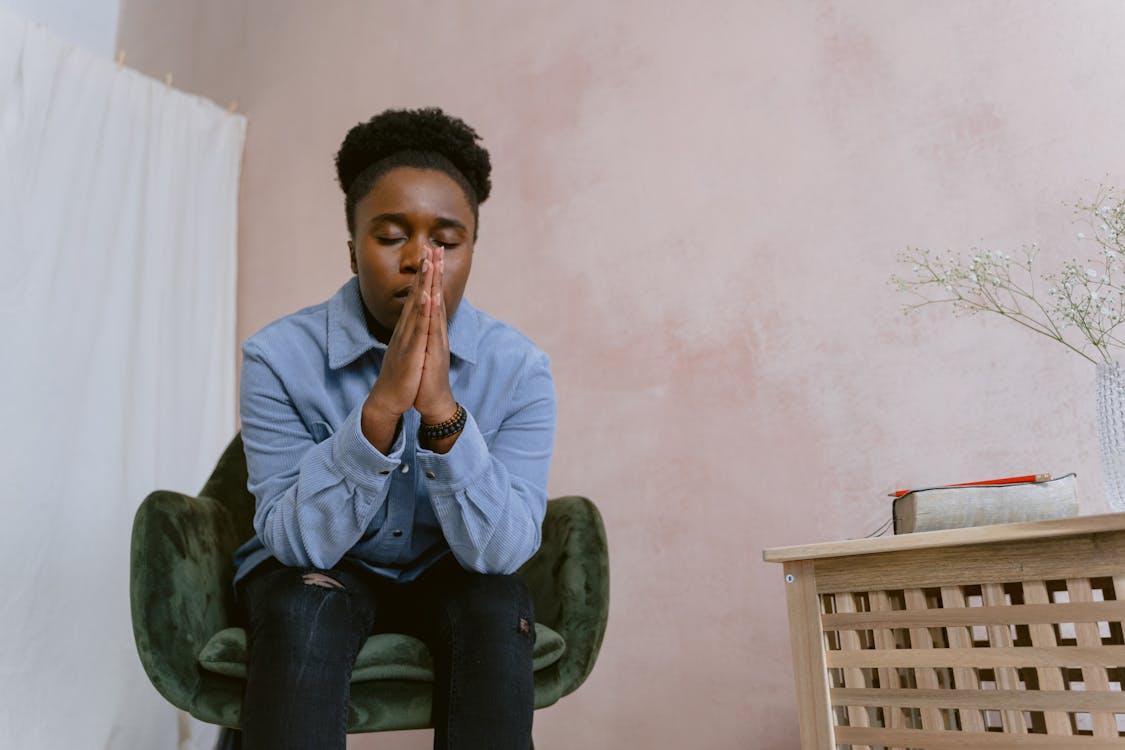 Free An Afro-Haired Woman Sitting on a Chair while Praying Stock Photo