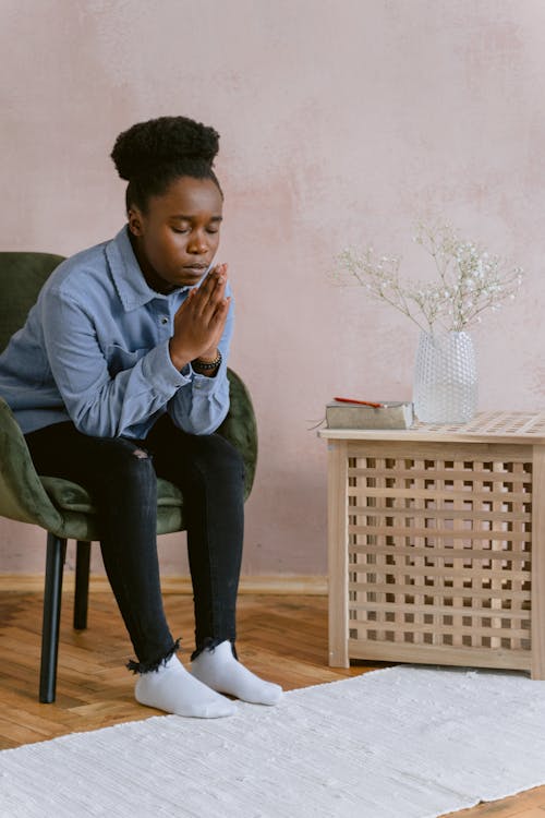 An Afro-Haired Woman Sitting on a Chair while Praying