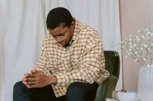 A Man Sitting on a Chair while Praying
