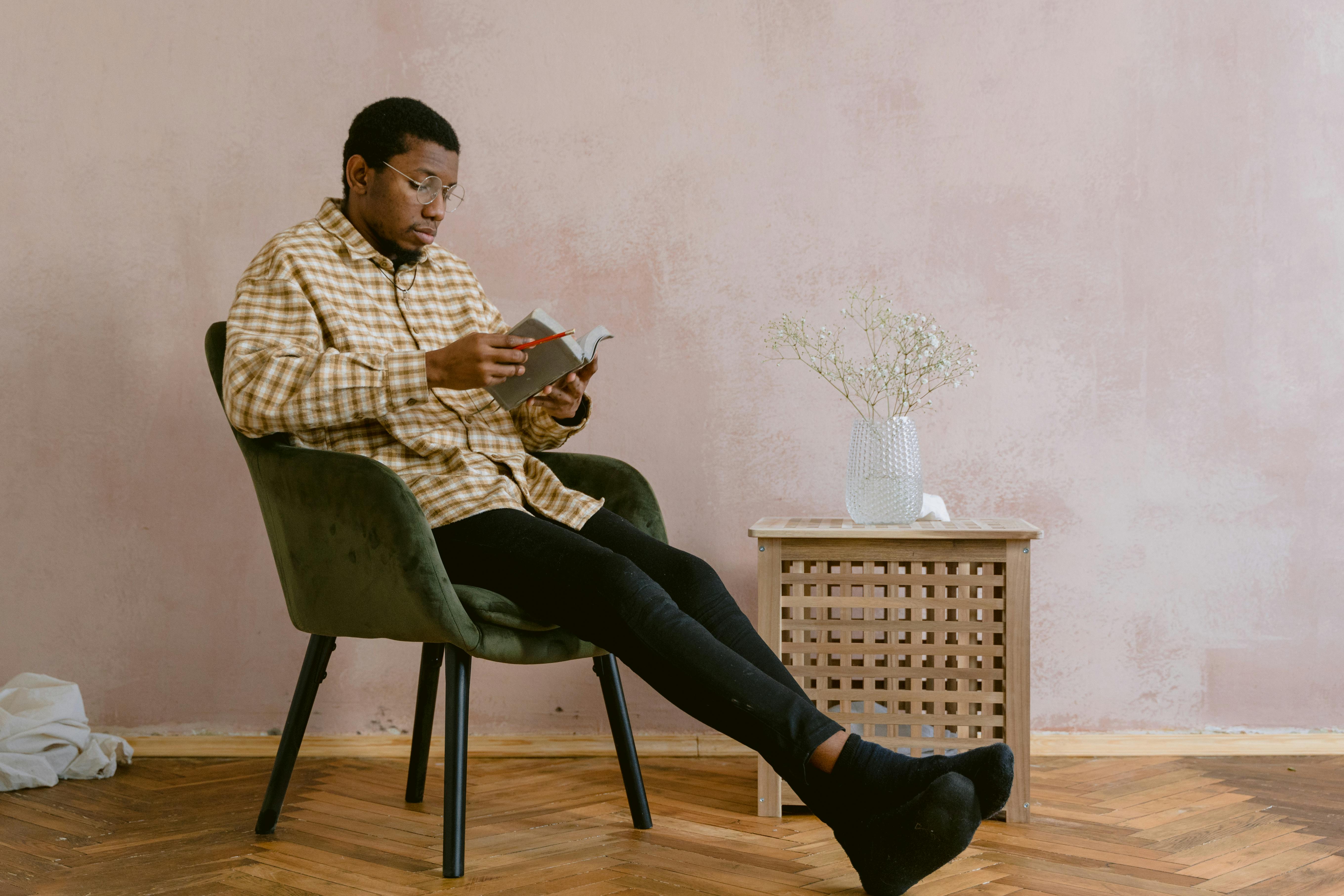 man in white and brown plaid button up shirt reading a bible