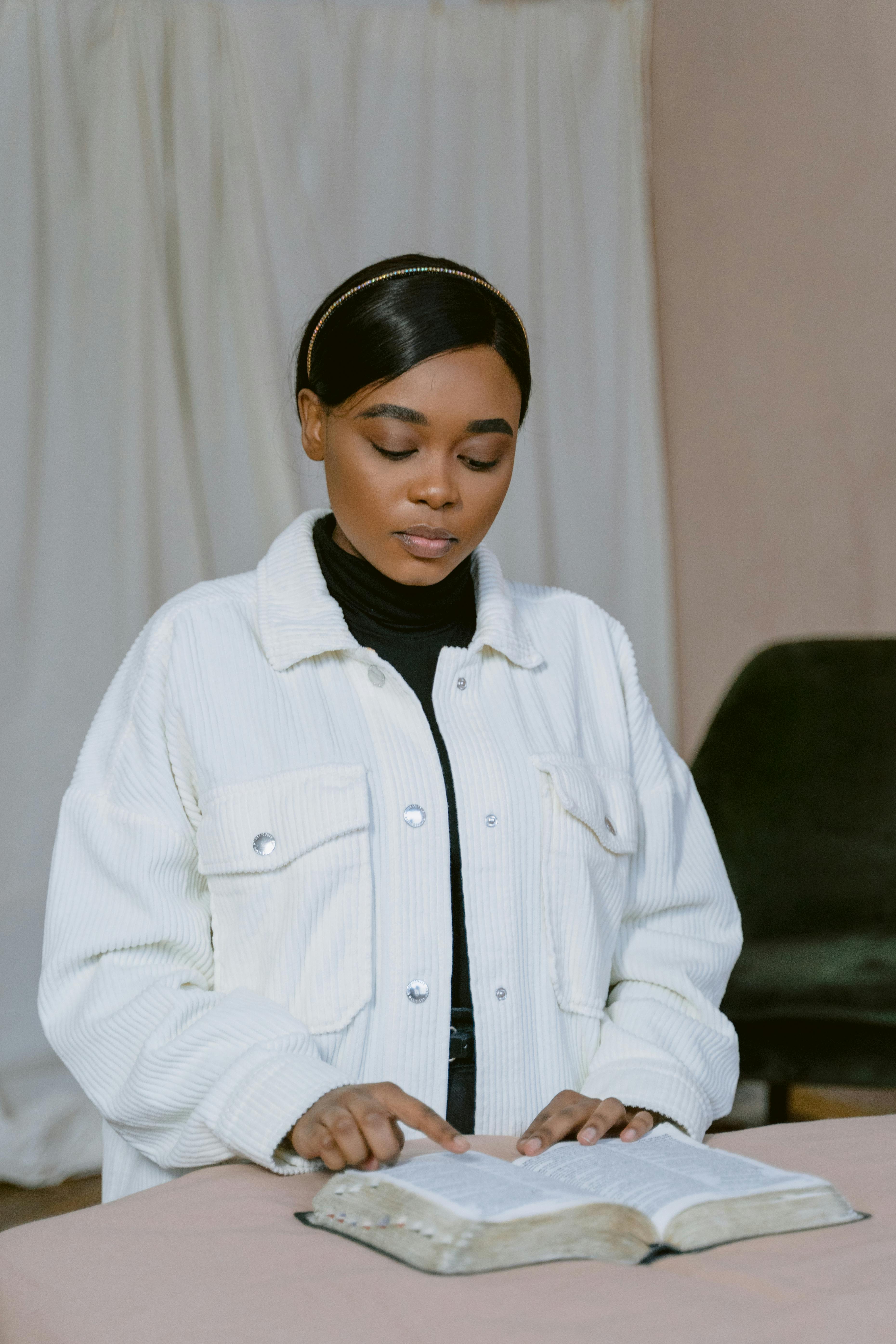 woman in white jacket reading a bible