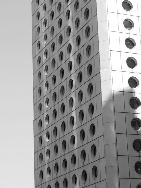 From below black and white exterior of tall building with geometric shaped circles on wall in city