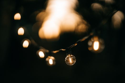 Close-up of hanging string light bulbs illuminating the dark with a cozy glow.