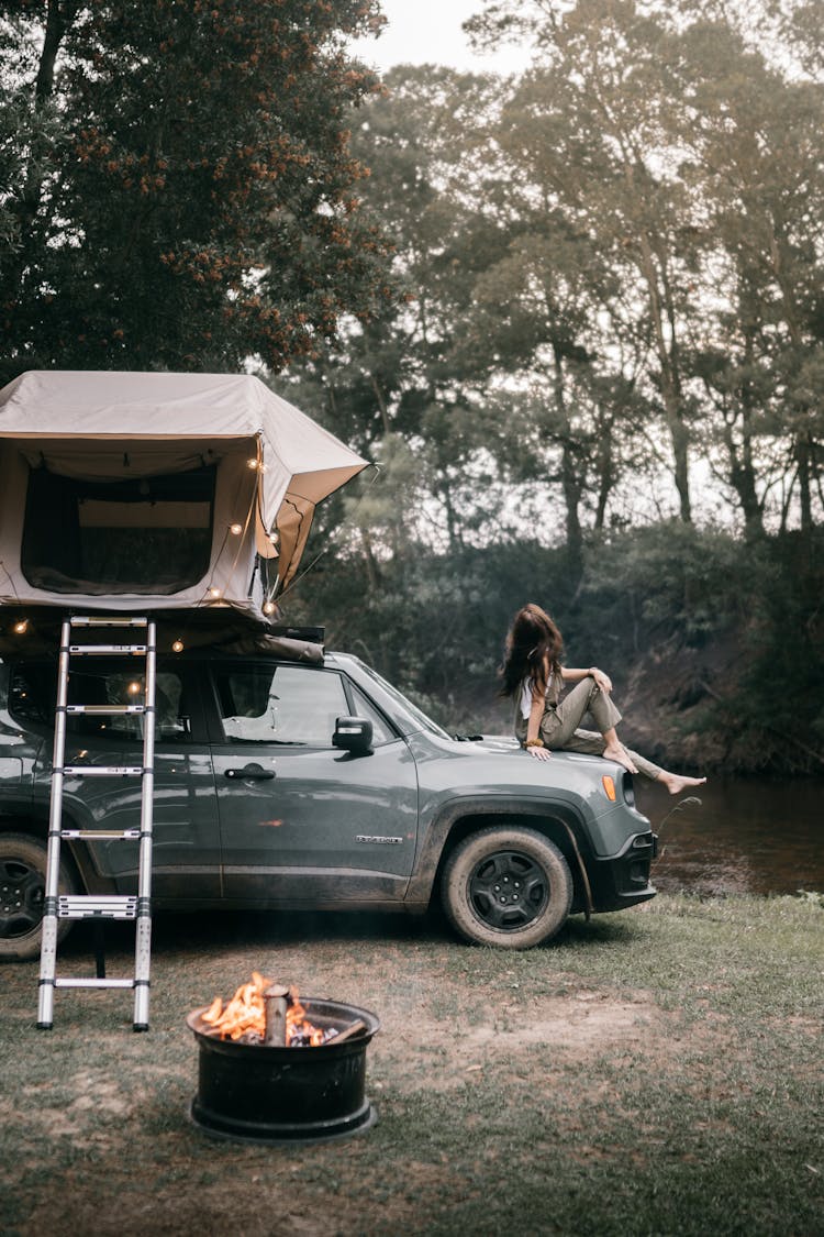 A Woman Sitting On The Hood Of The Car