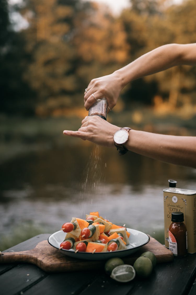 A Person Putting A Seasoning On Vegetables