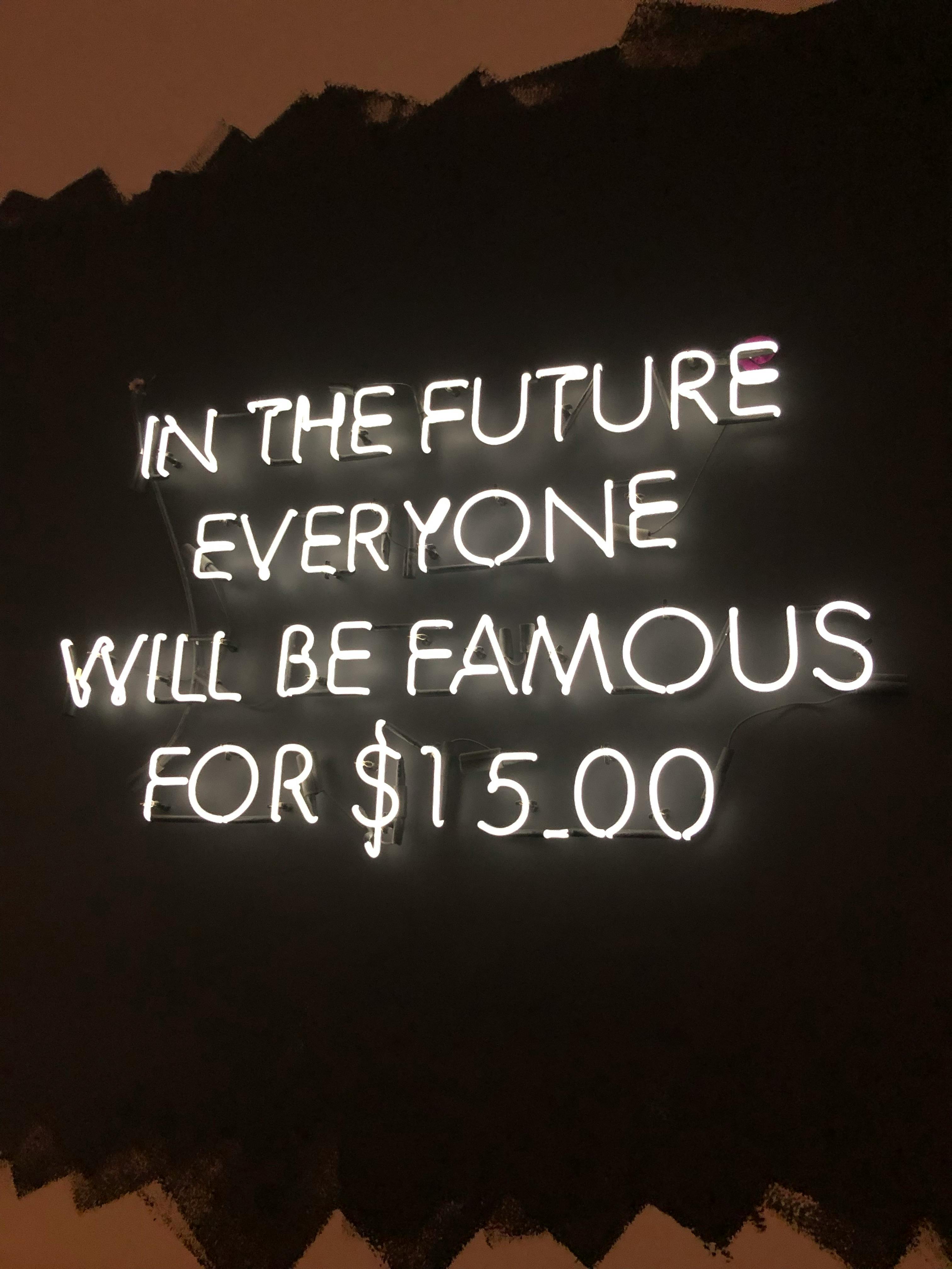Bright neon sign with a humorous quote about fame. Illuminates a modern, urban space with creative lighting.