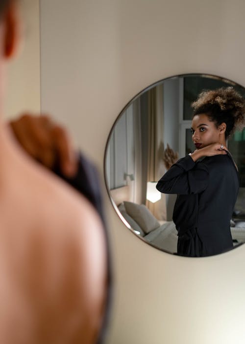 Free Woman in a Black Dress Looking at the Mirror Stock Photo