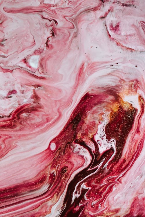 Overhead view of background representing artwork with curved pink and brown dye fluids and tiny dots