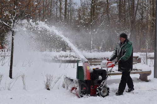 Free Man in Green Jacket Using Snow Blower Stock Photo