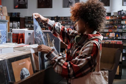 Woman in Red and White Plaid Shirt Checking the Vinyl Record