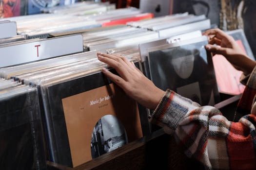 Close-up of hands browsing vinyl records in a cozy indoors music store.