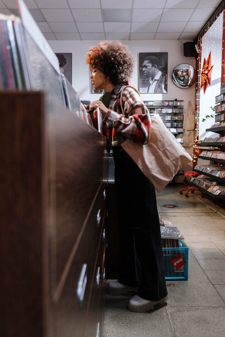 Woman Checking Vinyl Records At The Store