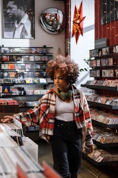 A young woman with afro hair browses vinyl records in a vintage retro shop.