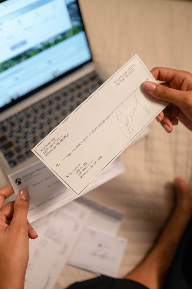 A Person's Hand Holding A Cheque