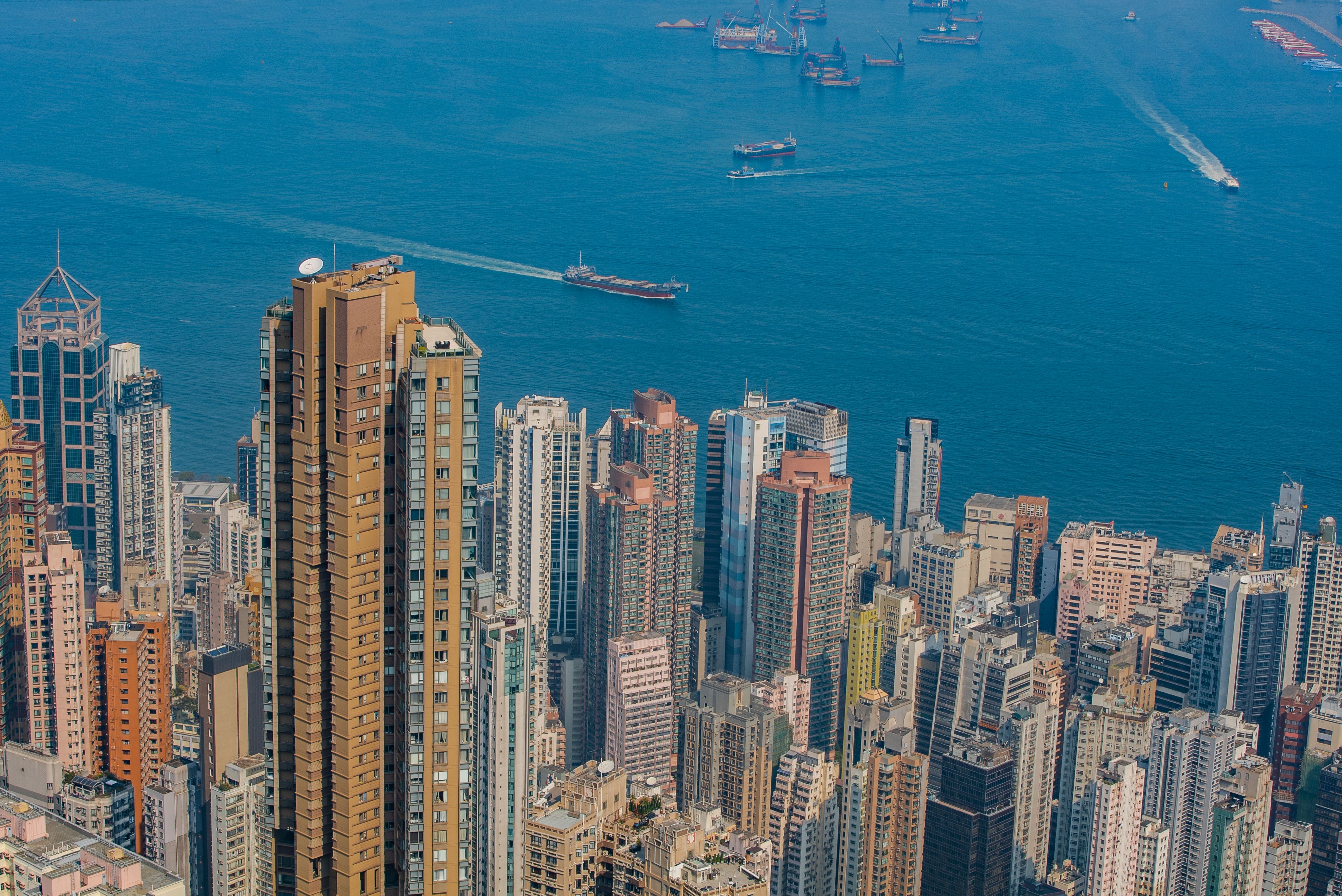 Aerial view of Hong Kong's urban skyline with high-rise buildings and Victoria Harbour.