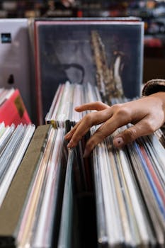Close-up of a hand browsing vinyl records in a vintage music store.