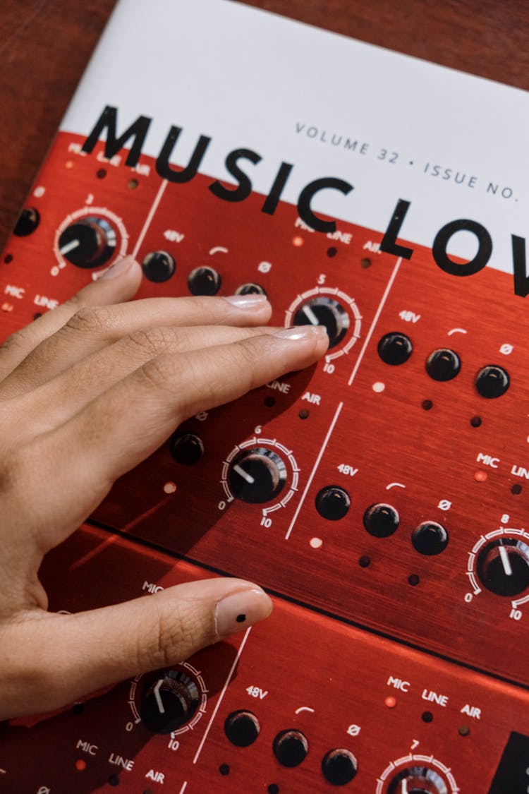 Person Touching A Music Magazine Cover With A Photo Of Synthesizer Knobs