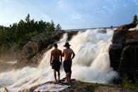 两名男子在自然光线下欣赏着被郁郁葱葱的森林包围的瀑布