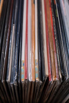 Close-up shot of classic vinyl records stacked in a collection, evoking nostalgia.
