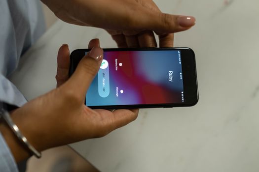 Close-up image of hands holding a smartphone receiving a call from Ruby on a marble surface. - Fotografer Sidoarjo