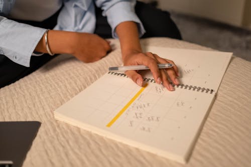 Free Close-Up Shot of a Person Writing on a Notebook Stock Photo