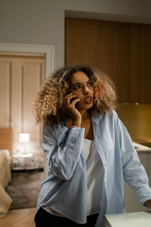 Free Adult woman with curly hair making a phone call indoors, lifestyle scene. Stock Photo