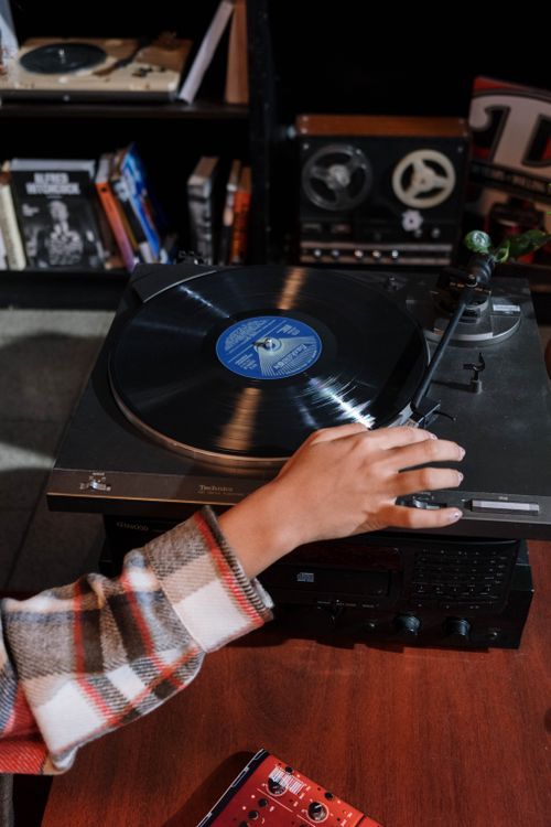 Free Close-up of a hand adjusting a vintage vinyl record player in a cozy room setting. Stock Photo