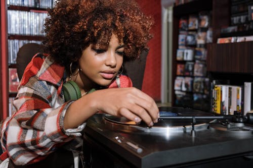 Woman in Plaid Shirt playing a Vinyl Record Player 
