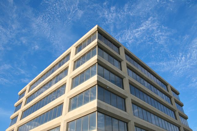 Corner view of a modern office building with reflective windows under a clear blue sky, illustrating the kind of post-29-October-2018 non-residential construction or acquisition that qualifies for Structures and Buildings Allowance