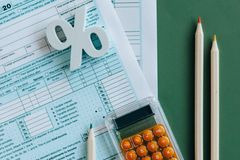 Flat lay of tax documents, calculator, and pencils on green surface.