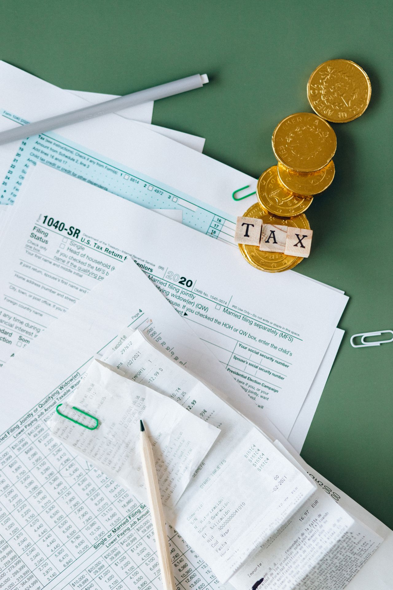Documentos fiscales y monedas sobre escritorio representando declaración de inversiones ante el SAT