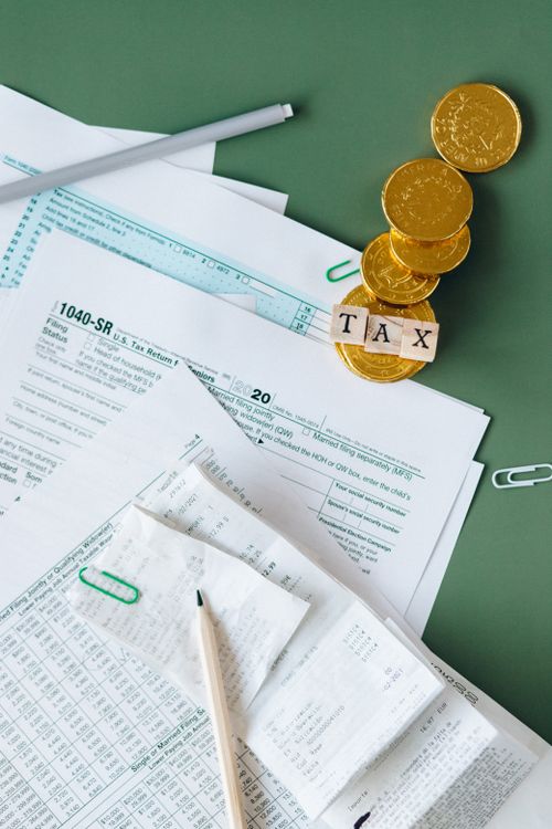 Free Tax documents and gold coins on a green desk symbolizing financial planning and savings. Stock Photo