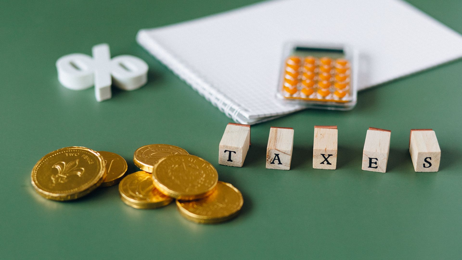Maximising Benefits Tips: Enhance Your Modafinil Experience Close-up of tax-related items including coins, calculator, and word 'taxes' on a green background — maximising benefits tips
