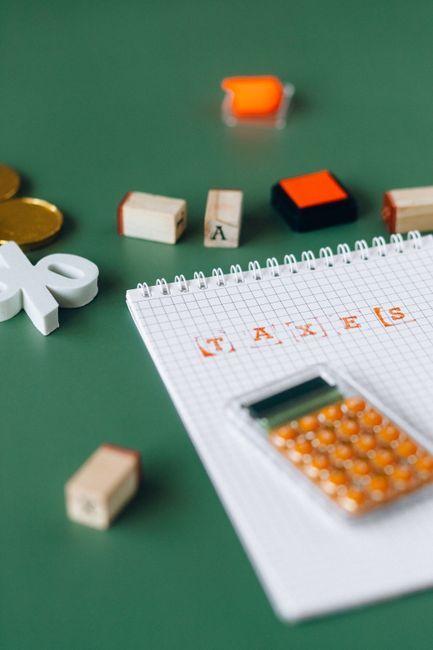 Close-up of calculator and stamped taxes on a notebook with green background. Close-up of calculator and stamped taxes on a notebook with green background.