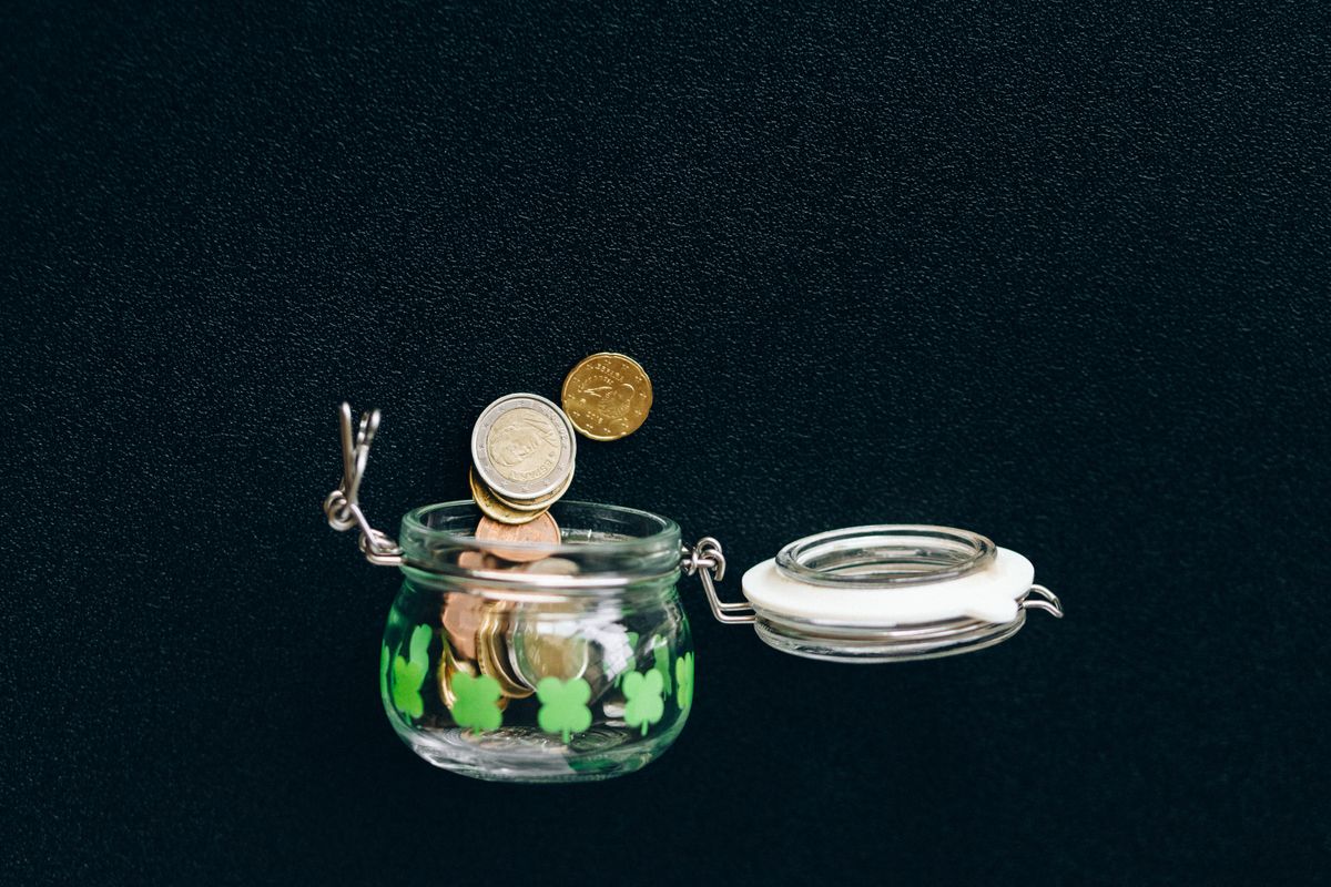 Glass jar with coins falling into it, symbolizing savings set aside