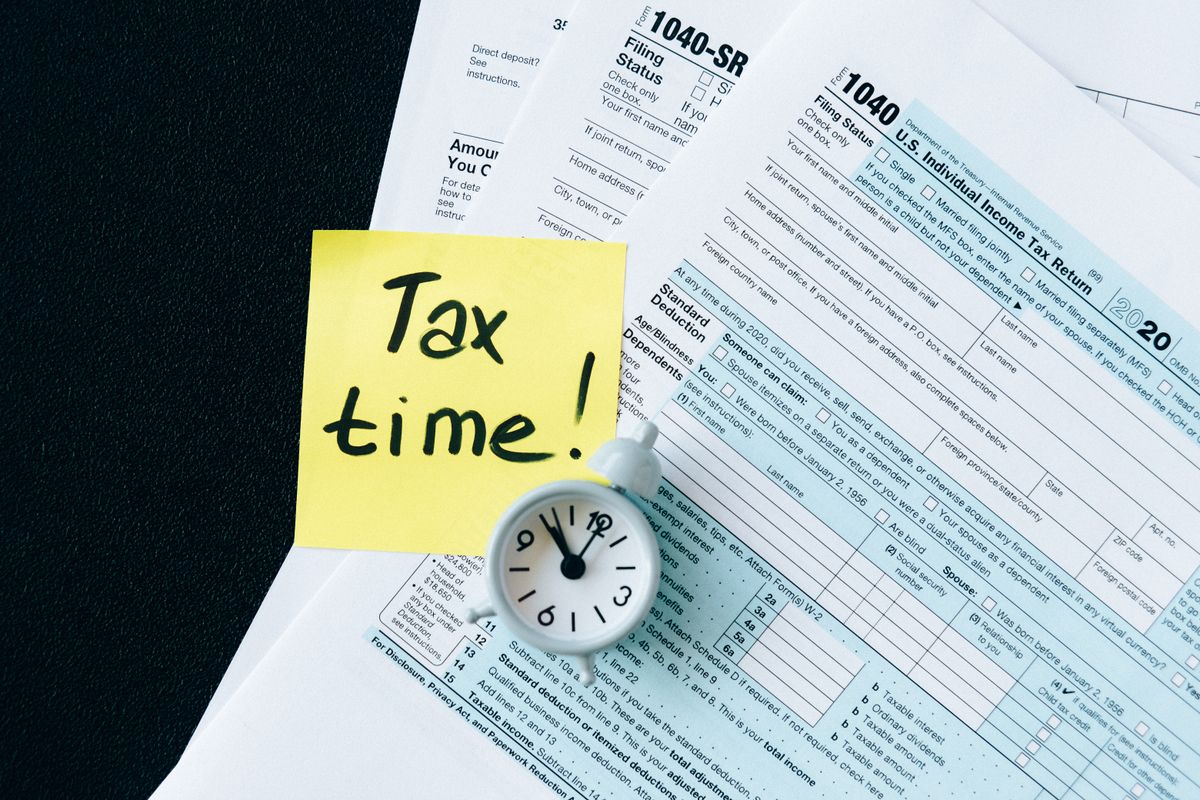 Tax forms on a desk with a sticky note that reads tax time