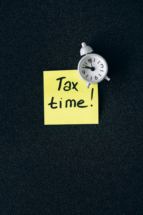 Free A clock on a sticky note with 'Tax time!' emphasizes importance of tax deadlines. Stock Photo
