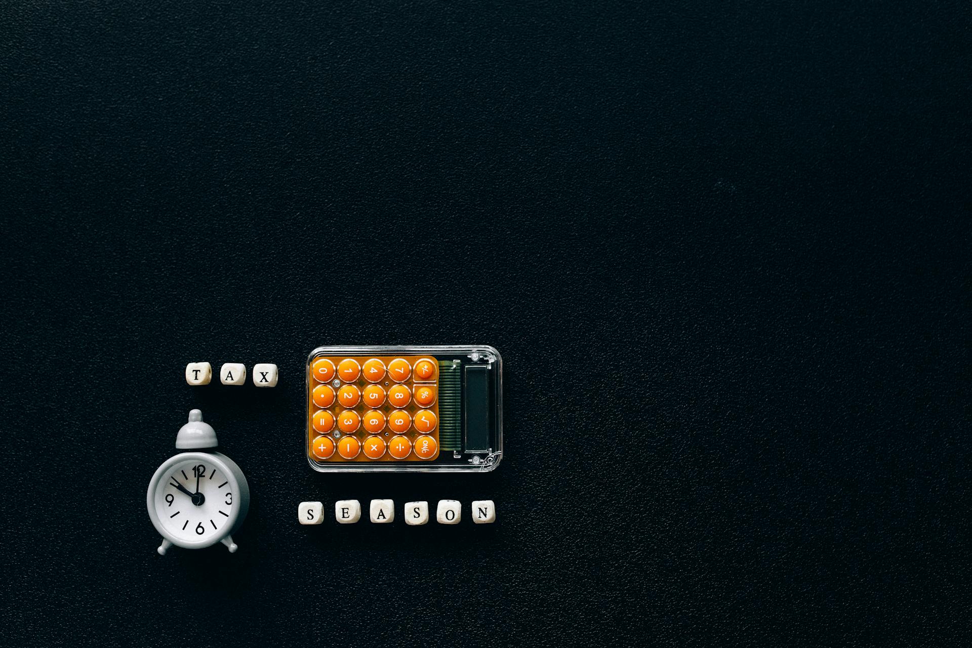 Flat lay of a tax season theme with a clock and calculator on a dark background.