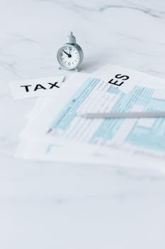 Tax documents and clock on marble, representing tax deadlines and financial concepts.