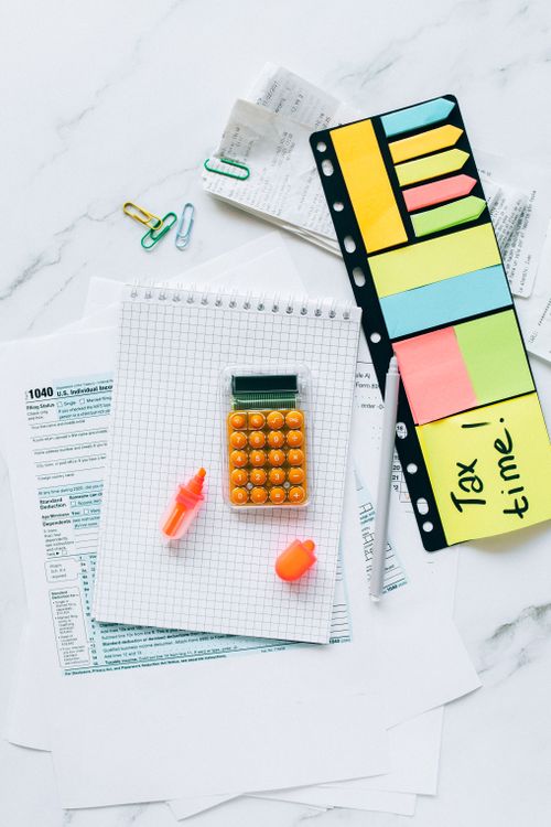 Free A vibrant tax preparation desk with documents, a calculator, and sticky notes for organization. Stock Photo