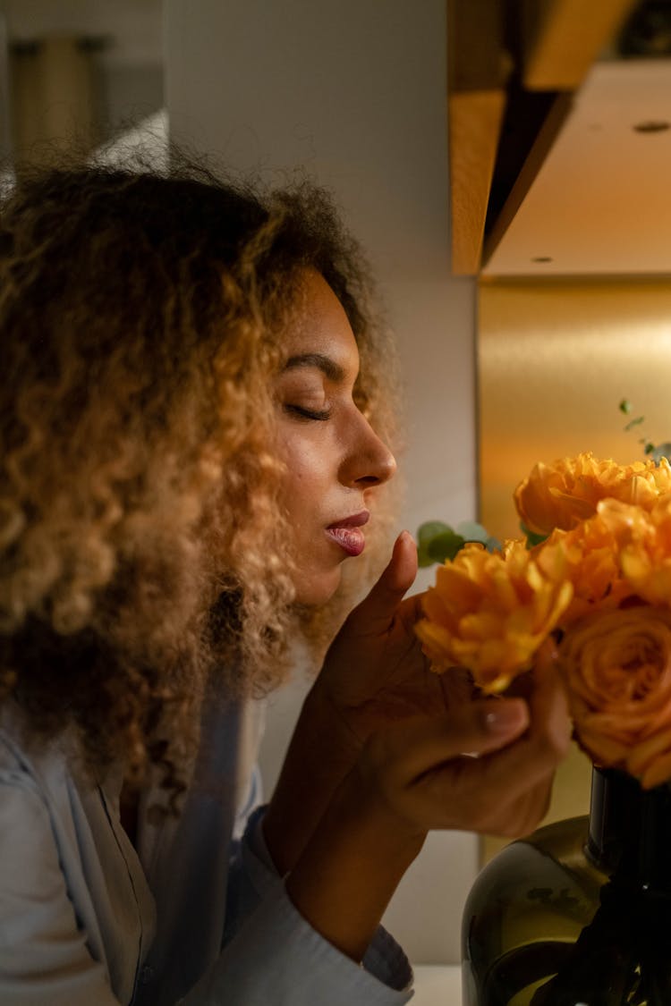 Woman Smelling Yellow Flowers In A Vase