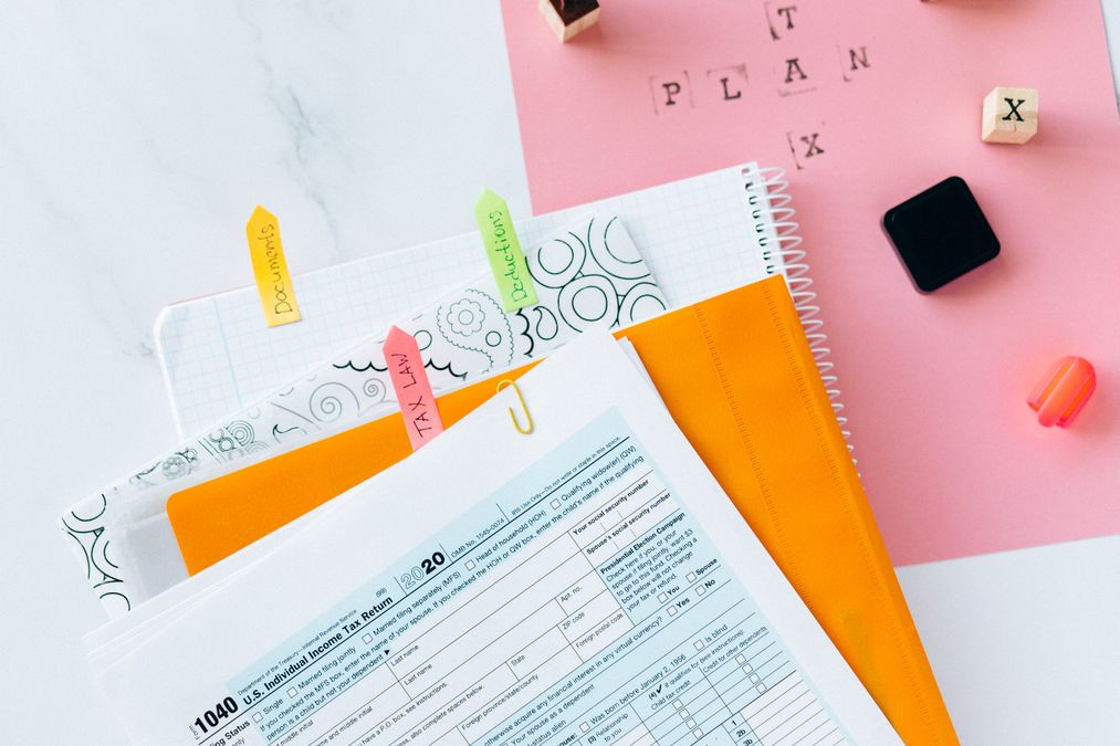 Formulário de declaração de imposto de renda sobre uma mesa, ao lado de cadernos, calculadora e documentos organizados