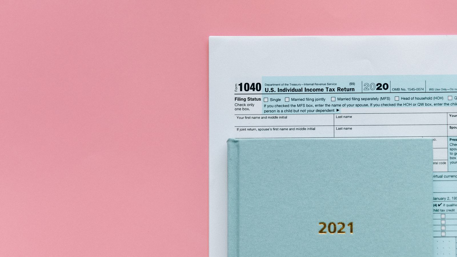 U.S. 1040 tax form with 2021 planner on a pastel pink background, symbolizing tax season.