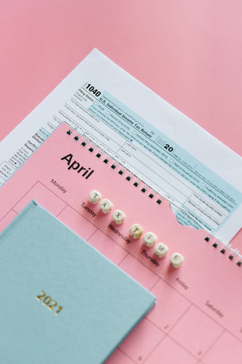 Free IRS Form 1040 and April planner on pastel background, symbolizing tax season. Stock Photo