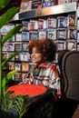 Woman in Red White and Blue Plaid Shirt Sitting on Chair Near Music Records