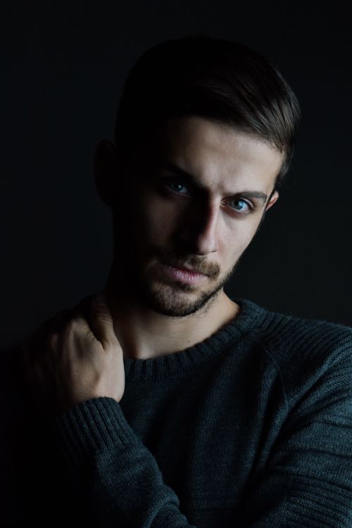 Free Intense studio portrait of a pensive man in dark lighting, looking thoughtful. Stock Photo