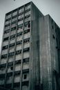 Multistory cement damaged house with corrosion and broken window located on street in neglected district of city against cloudless sky