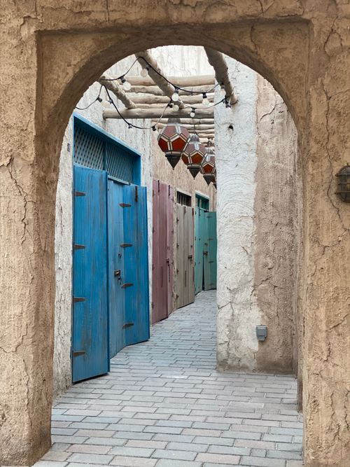 Free Charming narrow alleyway with rustic doors in vibrant colors, framed by an ancient archway. Stock Photo