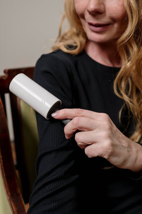Free Woman in Black Long Sleeve Shirt Holding a Lint Roller Stock Photo